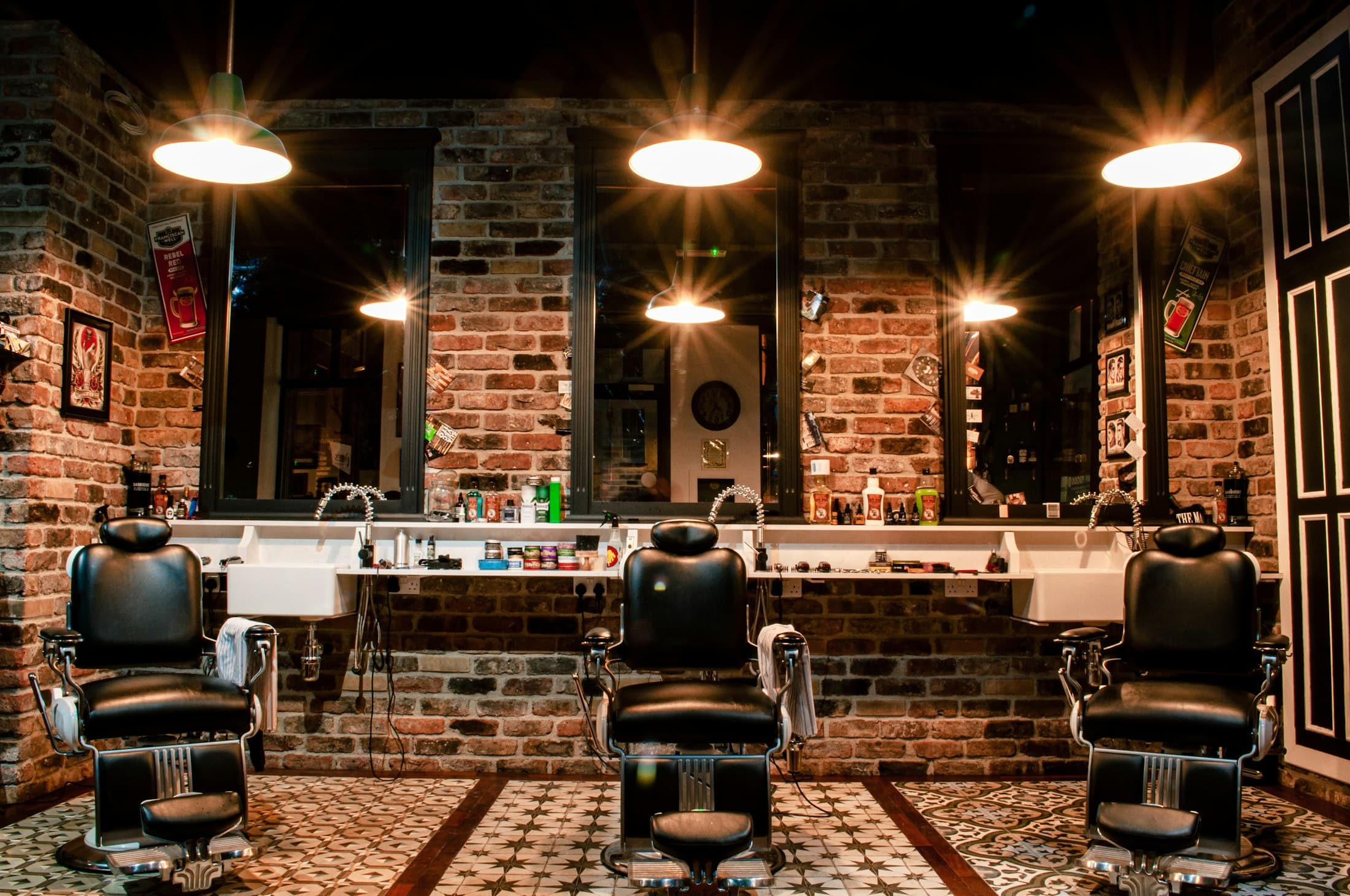 Interior de la barbería con sillas de cuero y luces colgantes